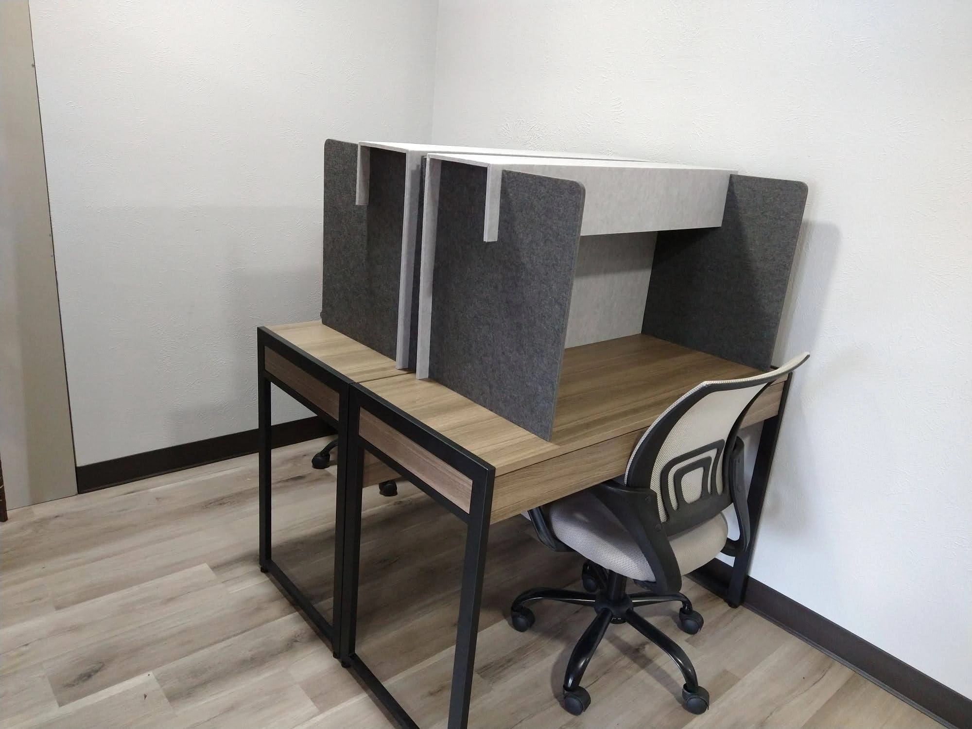 Coworking space in front lobby with two work desks with privacy screens and ergonimical chairs