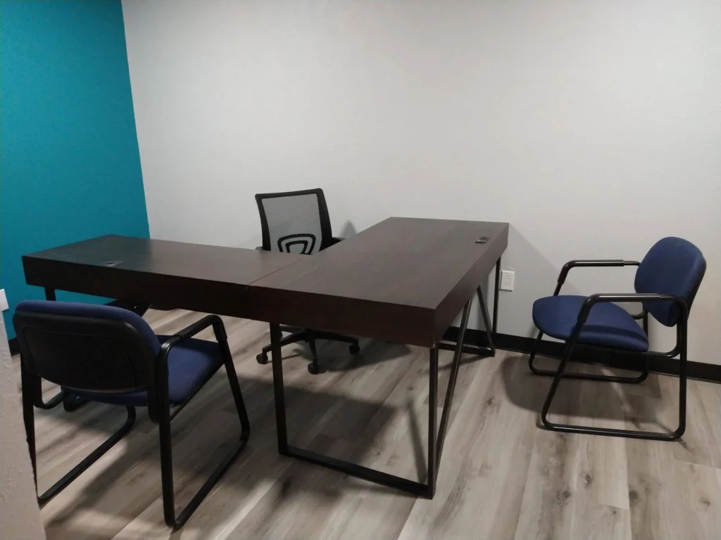 Private office, Suite C, with L-shaped dark brown desk, ergonomic desk chair, and two guest chairs