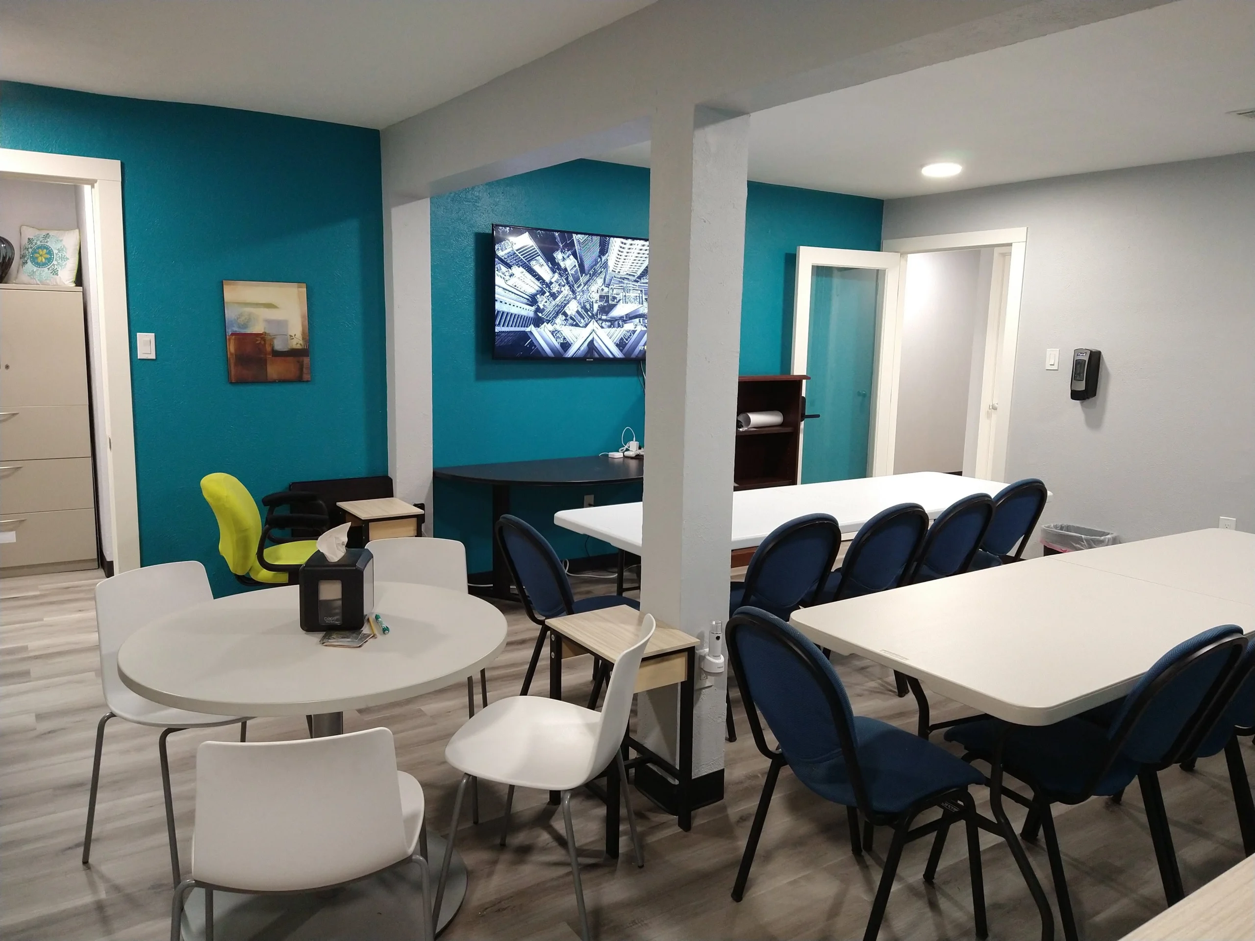 Flex room, view from side entry, with three tables with seating, plus Smart TV and presentation table